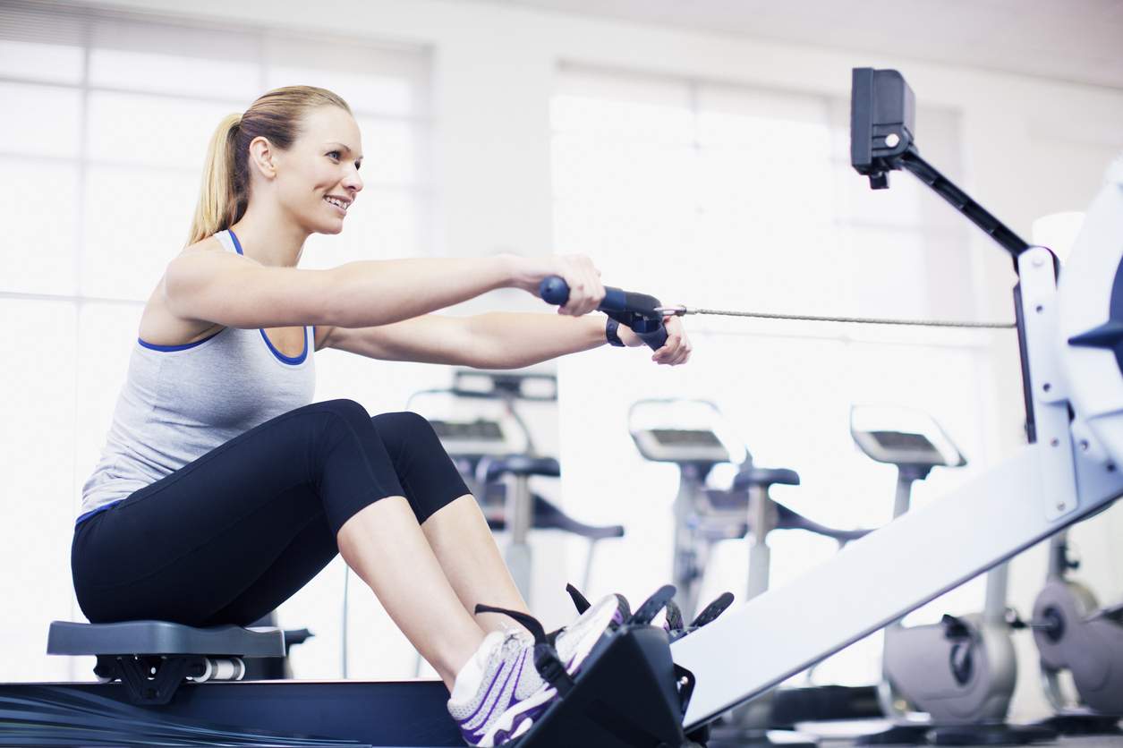 Woman exercising on rowing machine in gymnasium